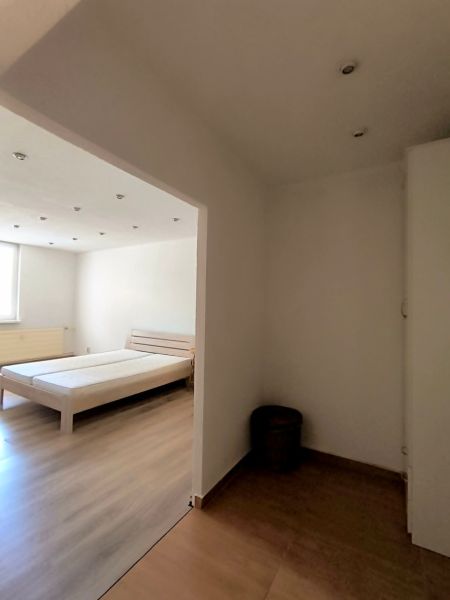 Interior of a 1-room apartment with a bed and a wooden decor floor.