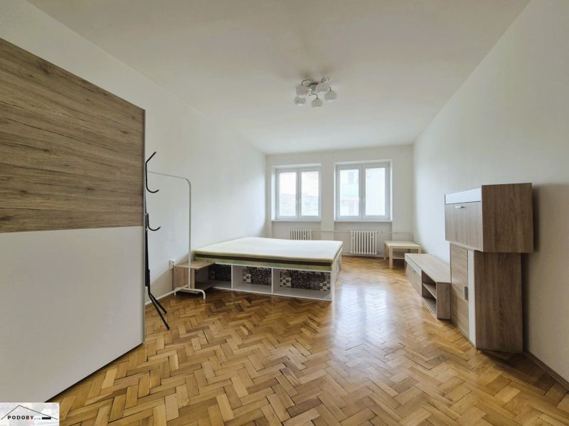 A room of a 3-room apartment with a bed and furniture, floor with wooden decor.