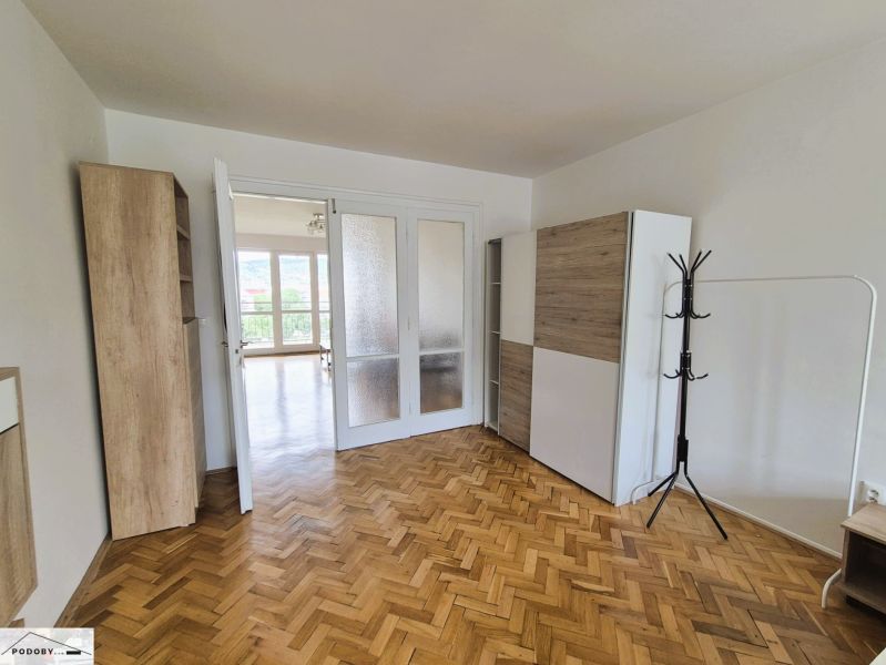 A room in a 3-room apartment with a wooden decor floor and white doors.