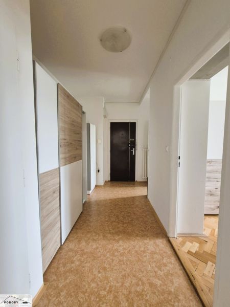 Entrance hallway with a built-in wardrobe and a floor with a wood decor in a 3-room apartment.