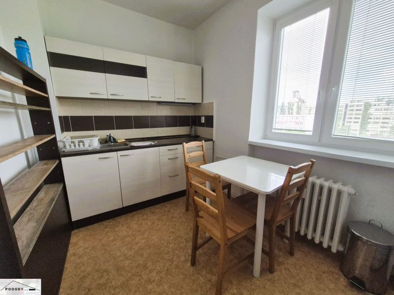 A kitchen with a kitchen unit, table, chairs, and a wood-decor floor in a 3-room apartment.