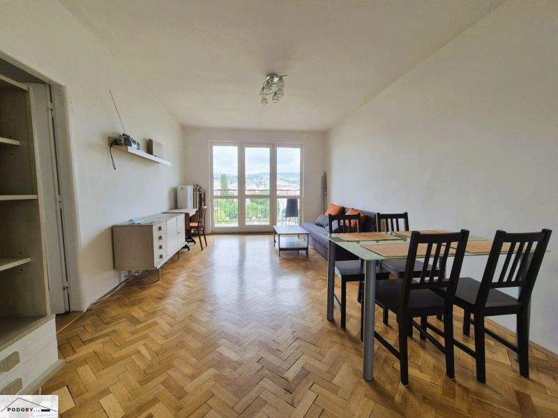Living room in a 3-room apartment with a wood-patterned floor and a dining table.