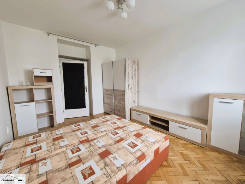 A bedroom with a bed, storage furniture, and a wooden decor floor in a 3-room apartment.