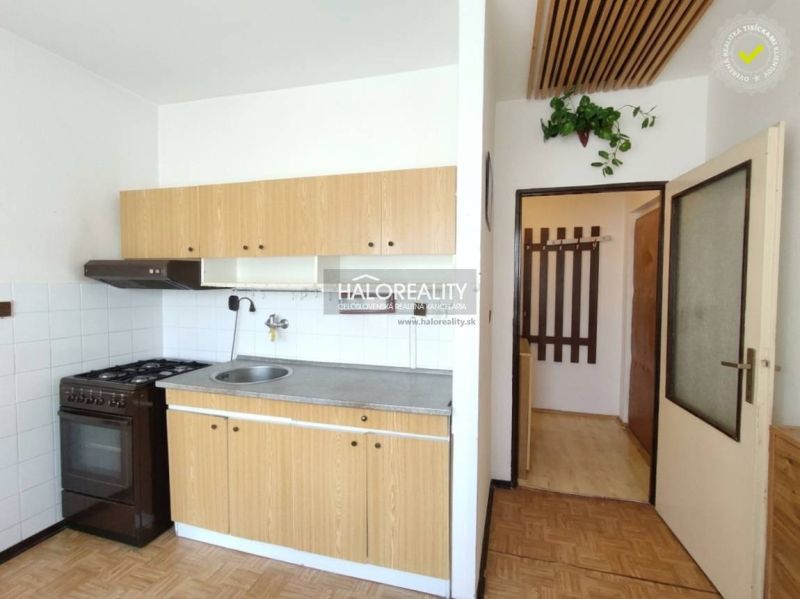 A kitchen in a studio apartment with wooden decor and simple equipment.