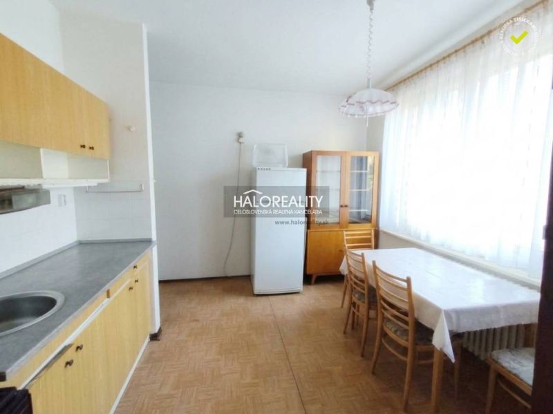 A kitchen in a studio apartment with a dining table and a wooden decor floor.