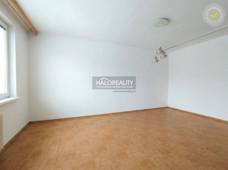 A room in a one-bedroom apartment with white walls and a wooden decor floor.
