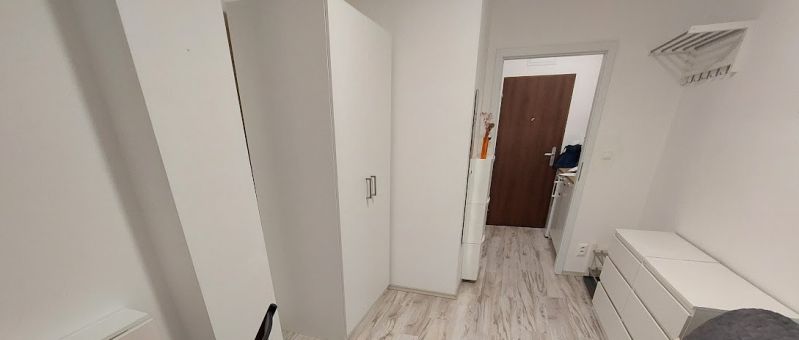 Cozy studio apartment with white furniture and a wood-patterned floor.