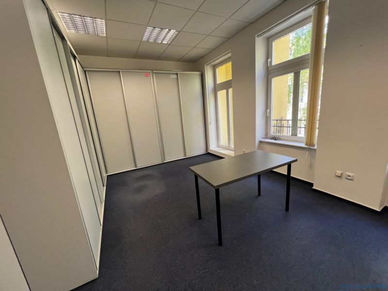 Offices with carpet, white walls, and a desk, large windows.