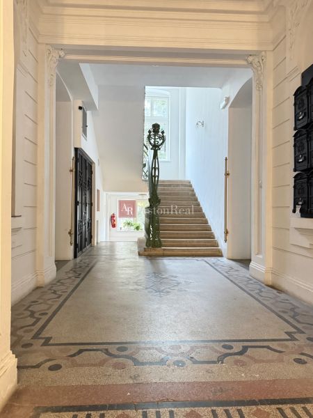 The entrance hall with a decorative floor leads to a staircase with a window.