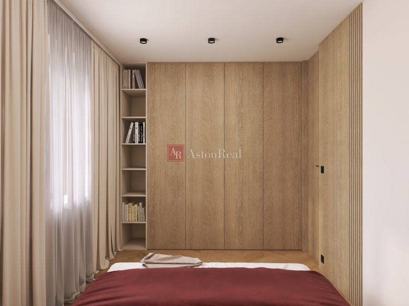 A bedroom with a wooden wardrobe, books, and curtains in a two-room apartment.
