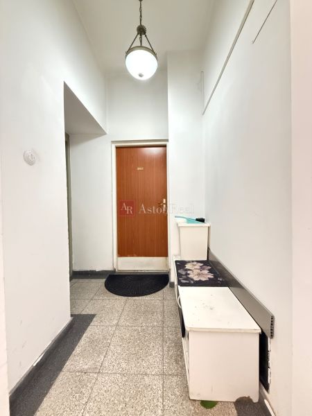 A corridor with white walls and brown doors in a 2-room apartment.