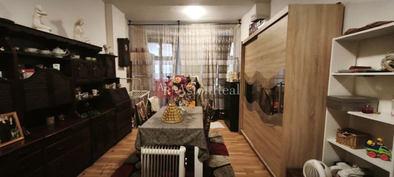 Living room in a two-room apartment with wooden decor flooring and rustic furniture.