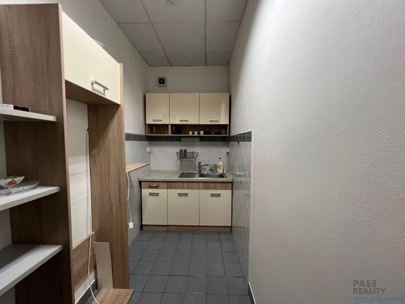 A narrow kitchenette in offices with a dining nook and storage shelves.