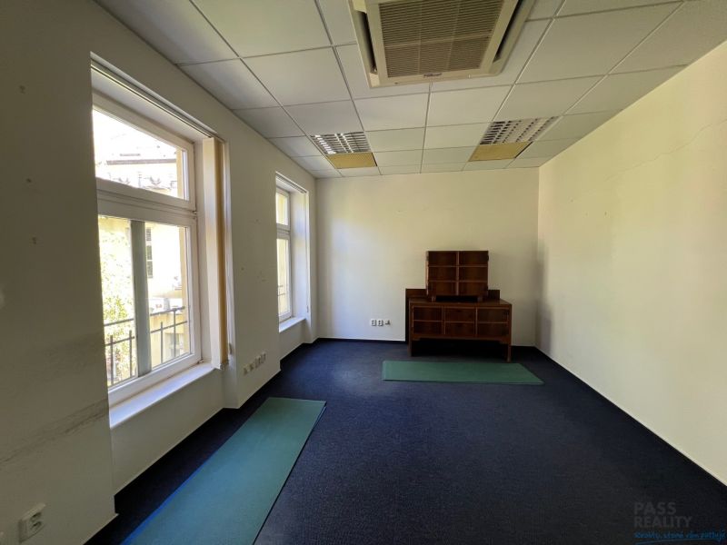 Offices with windows and carpeted floors, with wooden furniture.