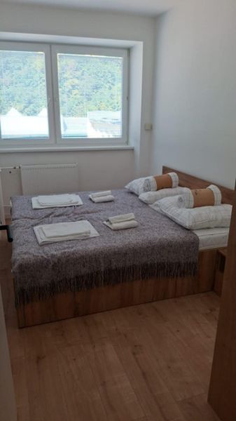 Bedroom with a bed and a window, wooden decor flooring in a 2-room apartment.