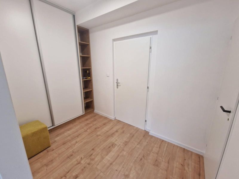 A hallway in a two-room apartment with a wooden decor floor and a built-in wardrobe.