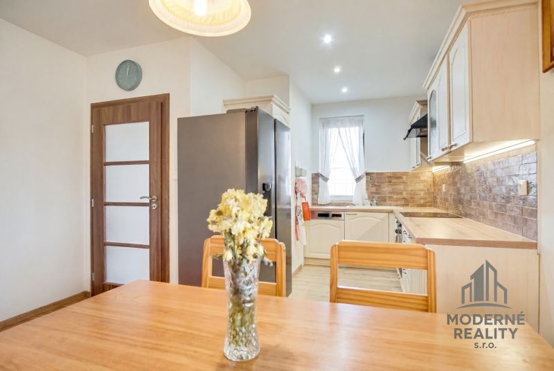 A kitchen in a family house with light furniture and decorative wall cladding.