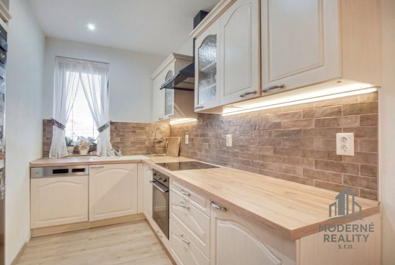 A kitchen in a family house with a wooden decor floor and brick cladding.