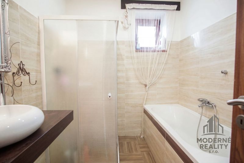 Bathroom with a bathtub, shower, and sink in a family house.