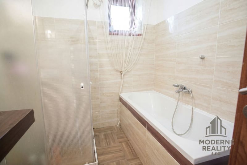 A bathroom in a family house with a bathtub and a shower.