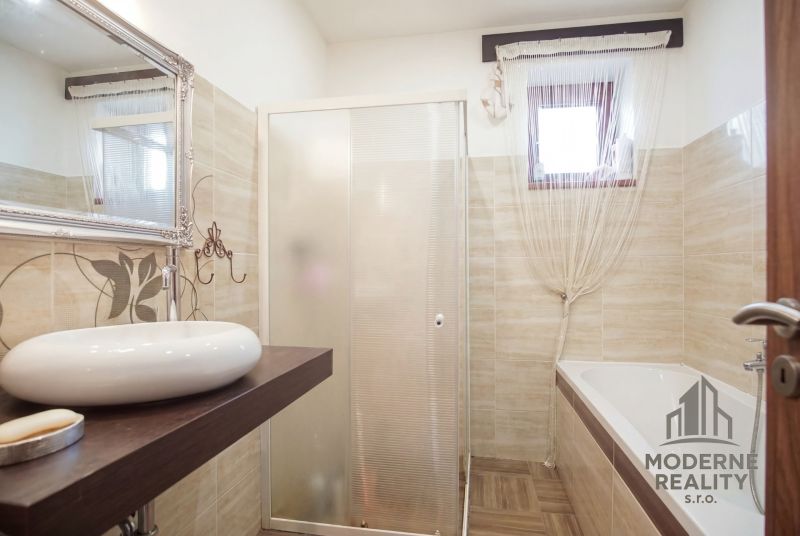 Bathroom in a family house with a bathtub, sink, and shower.