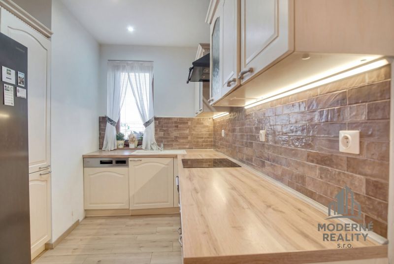 A kitchen in a family house with a countertop and brick wall cladding.