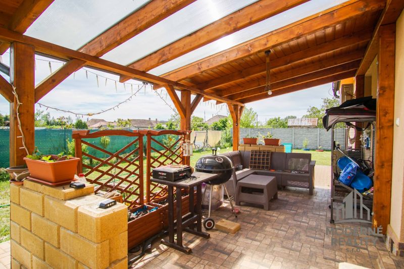In Andovce, there is a terrace with a grill and furniture under a wooden pergola by the family house.