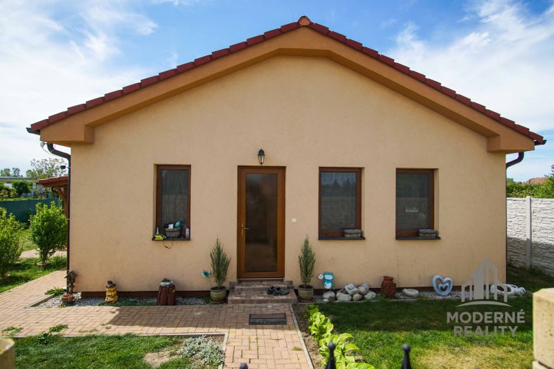 A family house in Andovce with three windows, a yard, and a flower bed.
