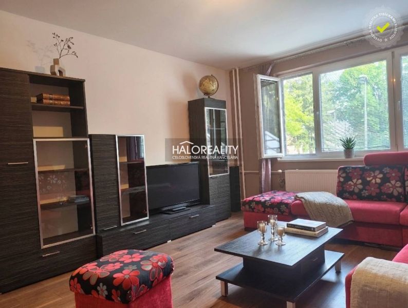 A living room in a three-room apartment with a wooden decor floor and vibrant colored furniture.