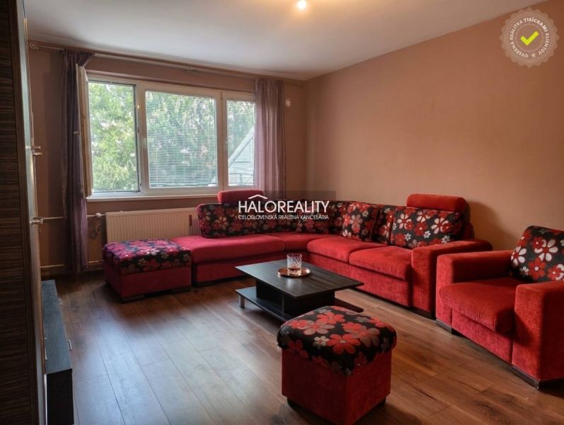 Living room in a 3-room apartment with a red sofa and a wooden decor floor.