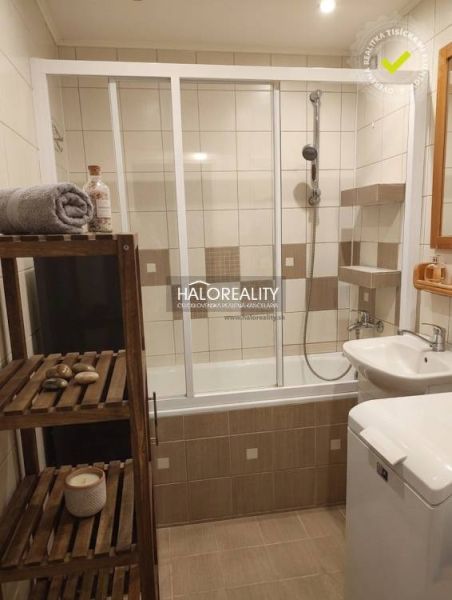 A bathroom in a 3-room apartment with a bathtub and shelves, complemented by a wooden rack.