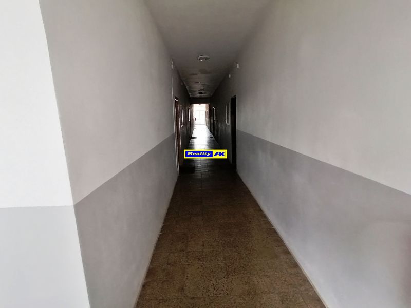 A long hallway with white walls and a tiled floor in a studio apartment.