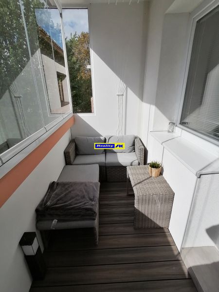 A glazed balcony with rattan furniture and a wooden decor floor in a studio apartment.