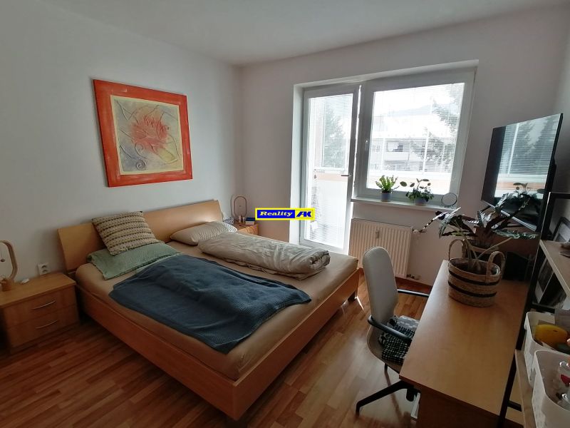 Bright 1-room apartment with wood-patterned flooring, a bed, and a table.