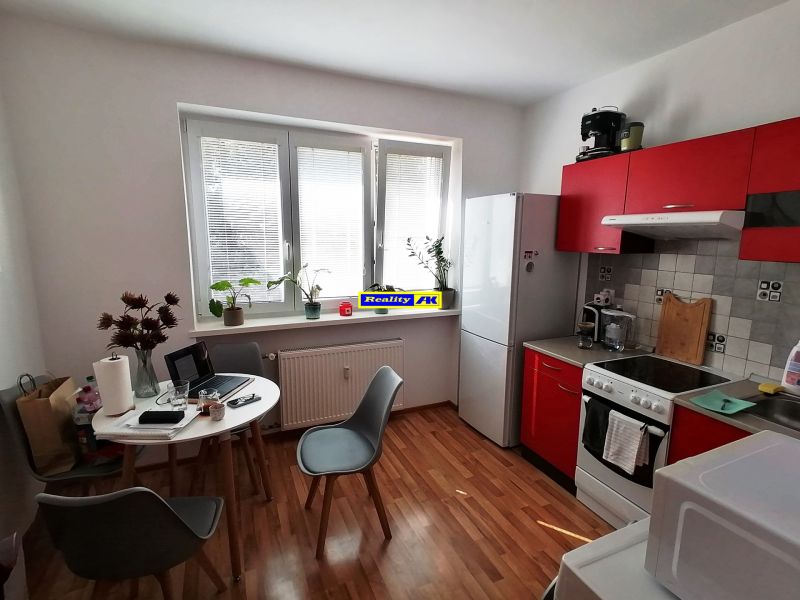 Kitchen in a studio apartment with a wooden decor floor and a red kitchen unit.