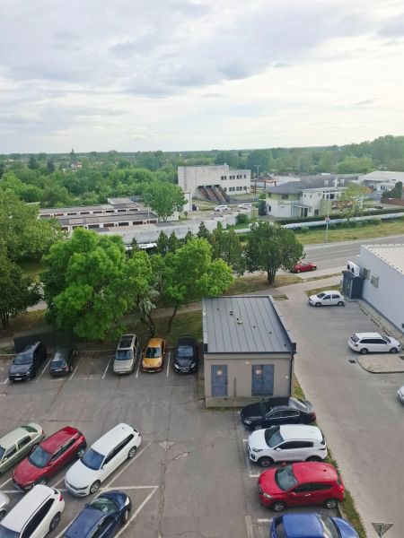 Parking lot with cars, greenery, and buildings in Nové Zámky on Nábrežná Street.