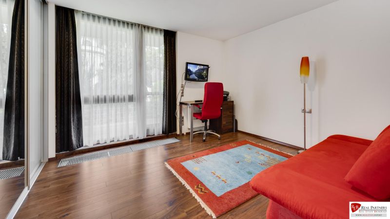 A bright room with a red sofa, a carpet, and a wooden decor floor.