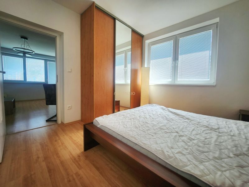 Bedroom with a large wardrobe and bed, wooden decor flooring in a 3-room apartment.