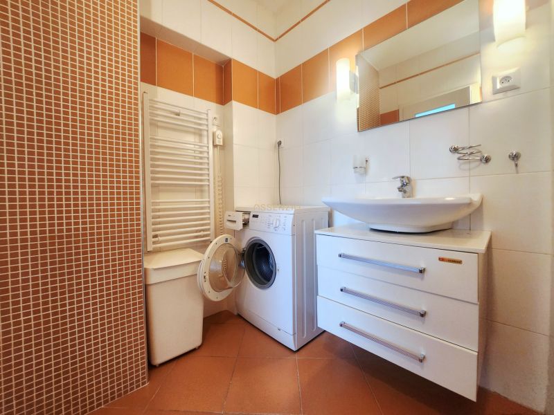 Bathroom with a washing machine and a sink in a 3-room apartment, tiles are in warm shades.