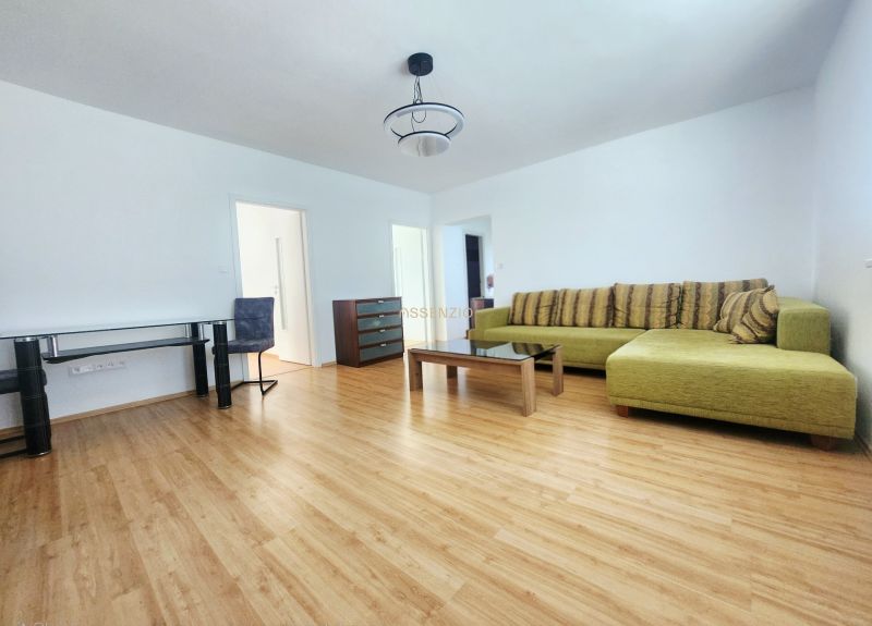 Living room with a sofa, table, and wooden decor flooring in a 3-room apartment.