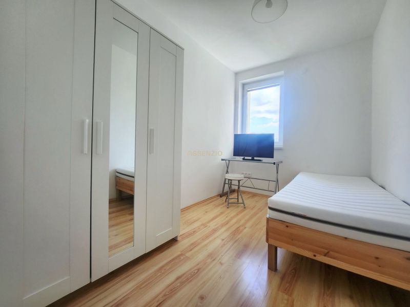 A bright room with a bed, a white wardrobe, and a television, a 3-room apartment, floor with wood decor.