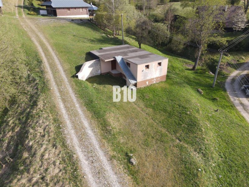A cottage in Zázrivá surrounded by green countryside and a dirt road.