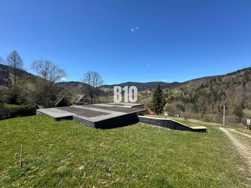 A cottage in Zázrivá with a view of wooded hills and a blue sky.