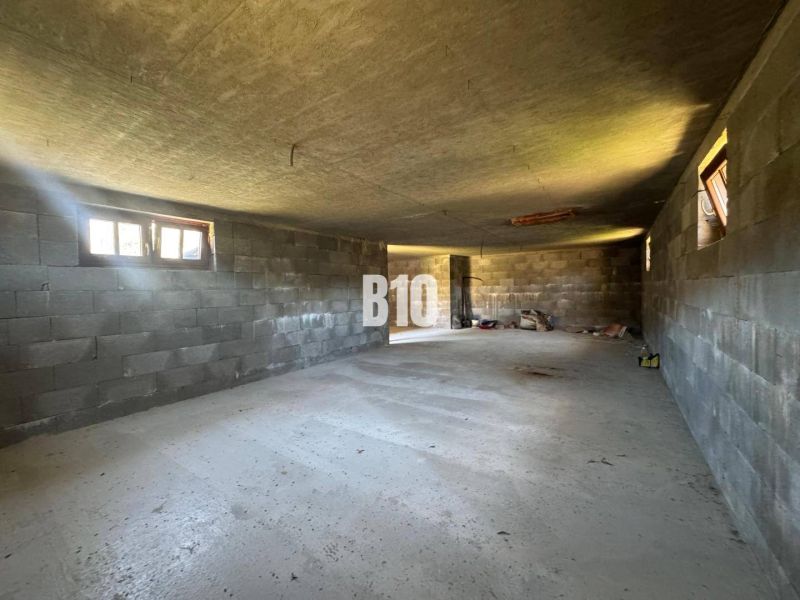 The interior of an unfinished cabin with concrete walls and floor.