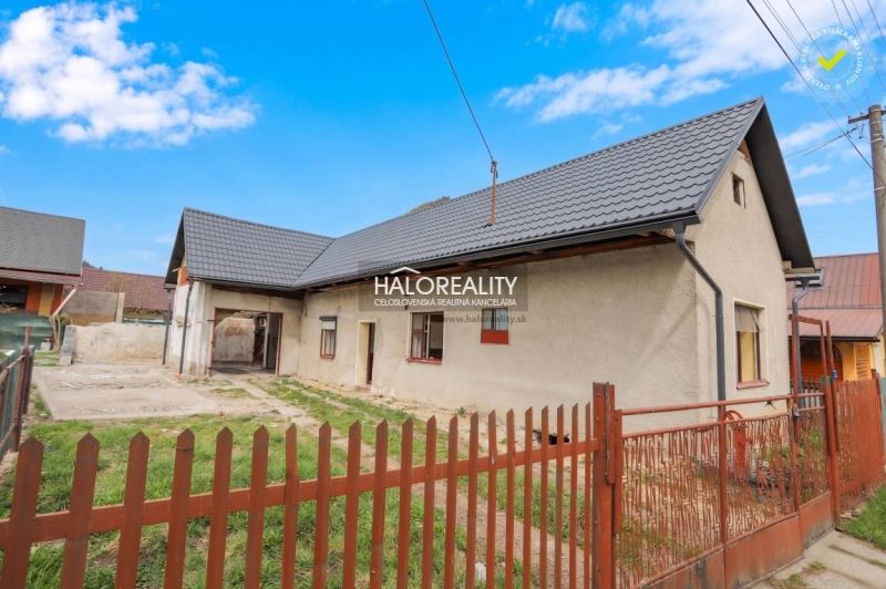 A family house in Stupno with a metal roof, two windows, and a solid fence.