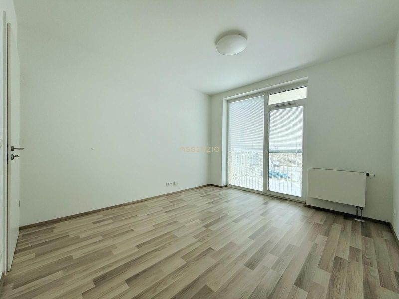 A room in a 2-room apartment with a wooden decor floor and access to a balcony.