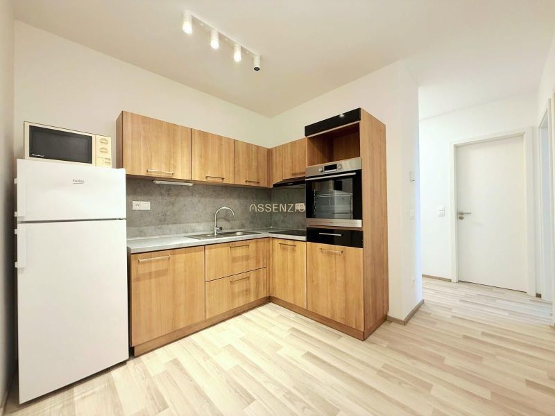 A kitchen in a 2-room apartment with wooden decor and appliances including a microwave.