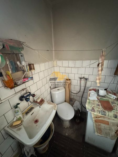 A bathroom in a family house with a sink, toilet, and an old washing machine.