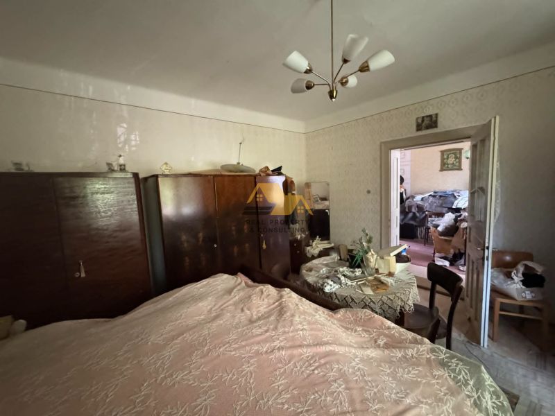 Bedroom in a family house with wardrobes and a table, bed with a decorative throw.