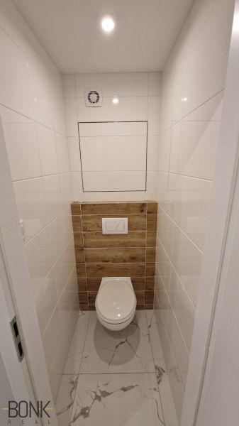 Bathroom section of a 2-room apartment with tiles and cladding in a wooden decor.